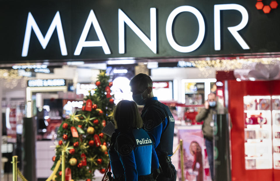 Police walk near the area where a stabbing occurred in a department store, in Lugano, Switzerland, Tuesday, Nov. 24, 2020. Swiss authorities are investigating as a possible terror attack the stabbing of two women in an department store in the southern city of Lugano, and a suspect has been arrested. Officials said one of the victims sustained serious but not life-threatening injuries, while the other sustained minor injuries. (Ti-Press/Keystone via AP)