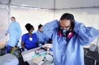 Mark Thompson, of Clearwater, dons a variety of PPE, including a respirator mask, before administering a COVID-19 viral test on Wednesday, May 6, 2020, at Community Health Centers of Pinellas, in Clearwater where Pinellas County began COVID-19 testing on Monday.(Douglas R. Clifford/Tampa Bay Times via AP)