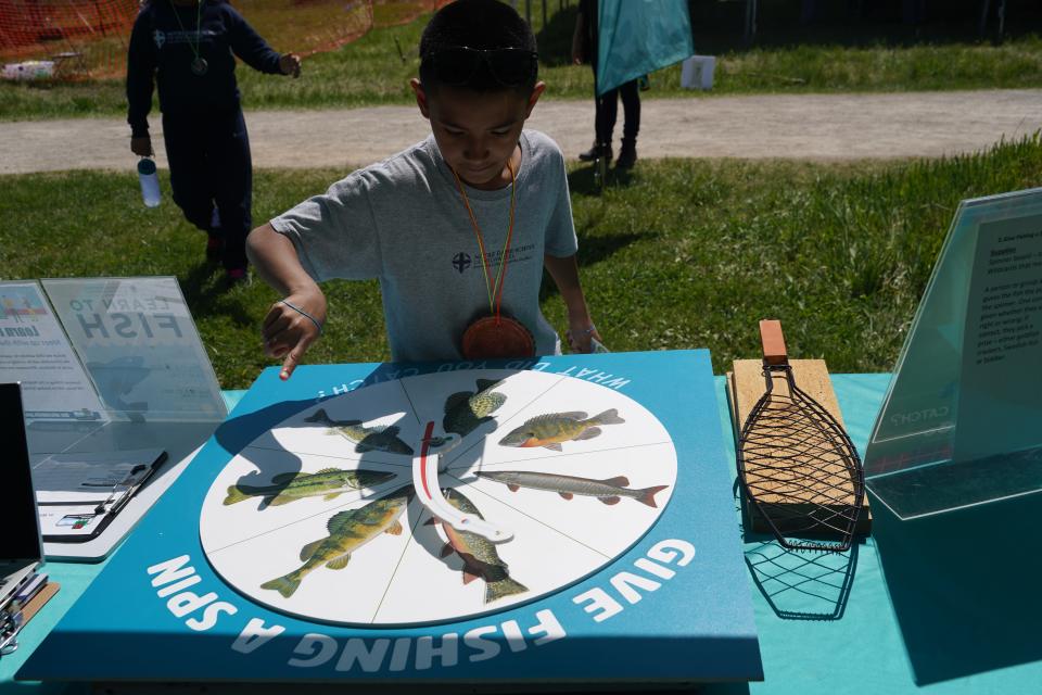 Fourth-grader Jesus Escoto of Milwaukee spins a fish identification wheel at a DNR booth at the Midwest Outdoor Heritage Education Expo in Milwaukee.