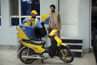 A postman delivers to a man in front of his house in the city of Kabul, Afghanistan, Wednesday, July 3, 2024. In parts of Afghanistan where there are no street names or house numbers, utility companies and their customers have adopted a creative approach for connecting. They use mosques as drop points for bills and cash, a "pay and pray" system. (AP Photo/Siddiqullah Alizai)