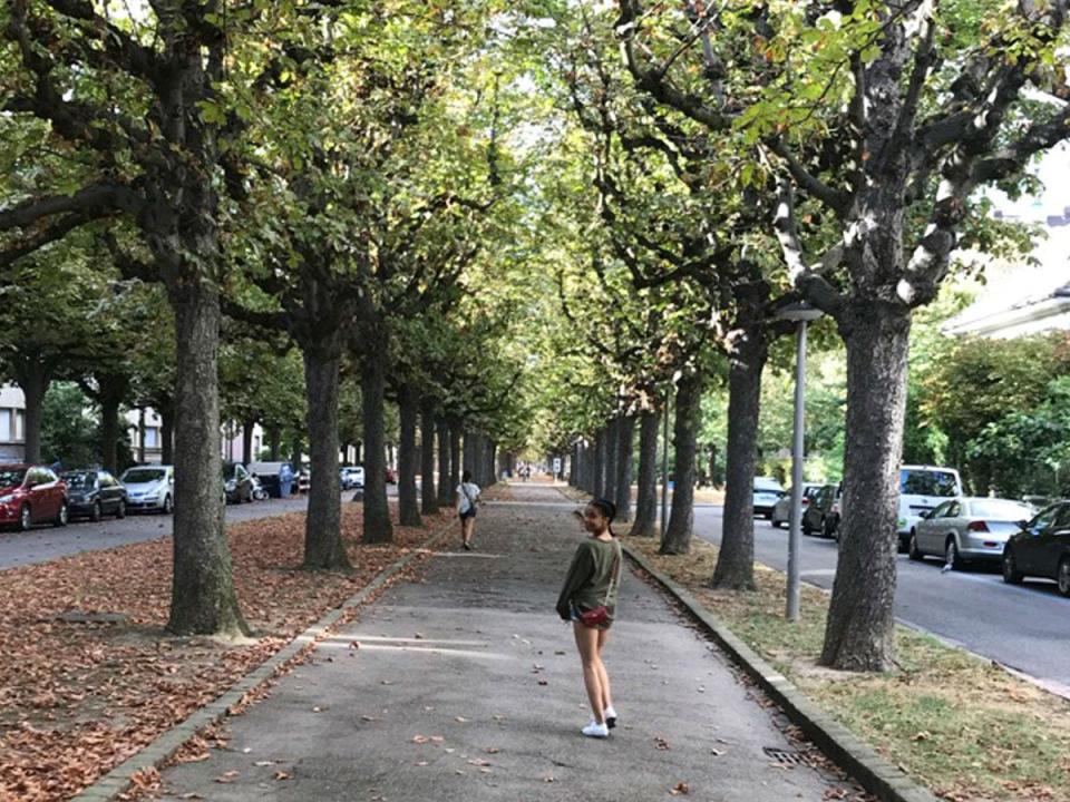 celeste polanco walking down a park in switzerland, smiling over her shoulder