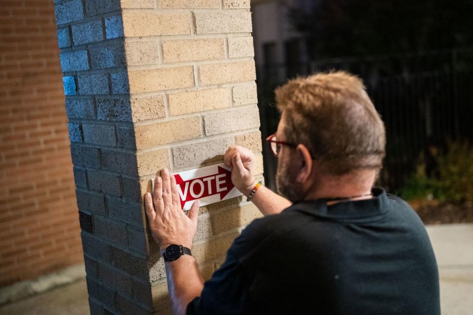 A person attaching an arrow sign to a pillar