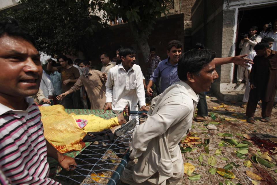 Men carry an injured women on a stretcher at the site of a suicide blast at a church in Peshawar