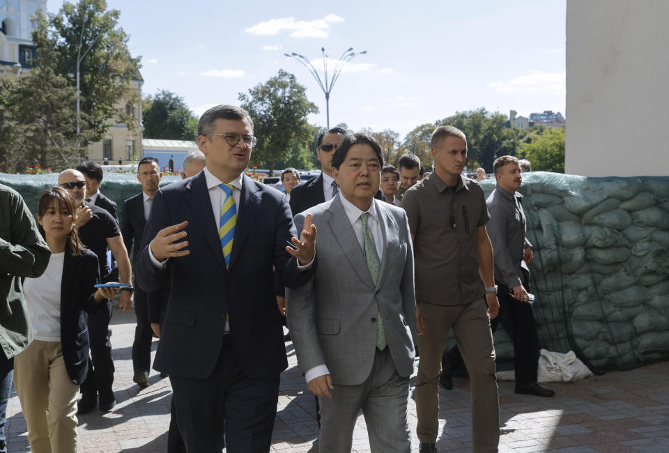 Ukraine's Foreign Minister Dmytro Kuleba, left, and his Japanese counterpart Yoshimasa Hayashi walk past bags with sand during their meeting in Kyiv, Ukraine, Saturday, Sept. 9, 2023. Japanese Foreign Minister Hayashi arrived in Ukraine's capital for an unannounced visit where he will meet with top Ukrainian officials. (Sergey Dolzhenko/pool via AP)