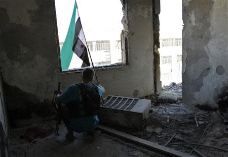 A Free Syrian Army fighter uses a Syrian opposition flag to attract and locate snipers loyal to Syria's President Bashar al-Assad in Aleppo's Qastal al-Harami neighbourhood September 11, 2013. REUTERS/Nour Kelze