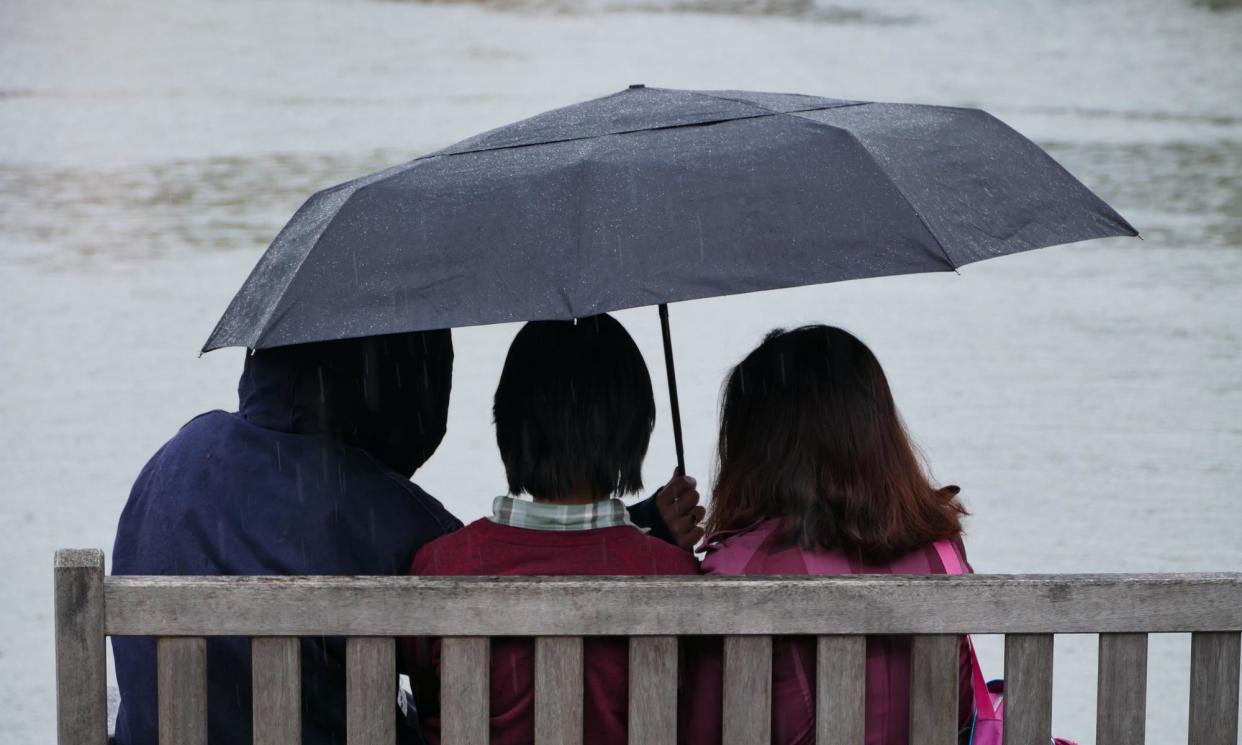 <span>People sheltering under an umbrella in Henley-on-Thames, Oxfordshire.</span><span>Photograph: Geoffrey Swaine/REX/Shutterstock</span>