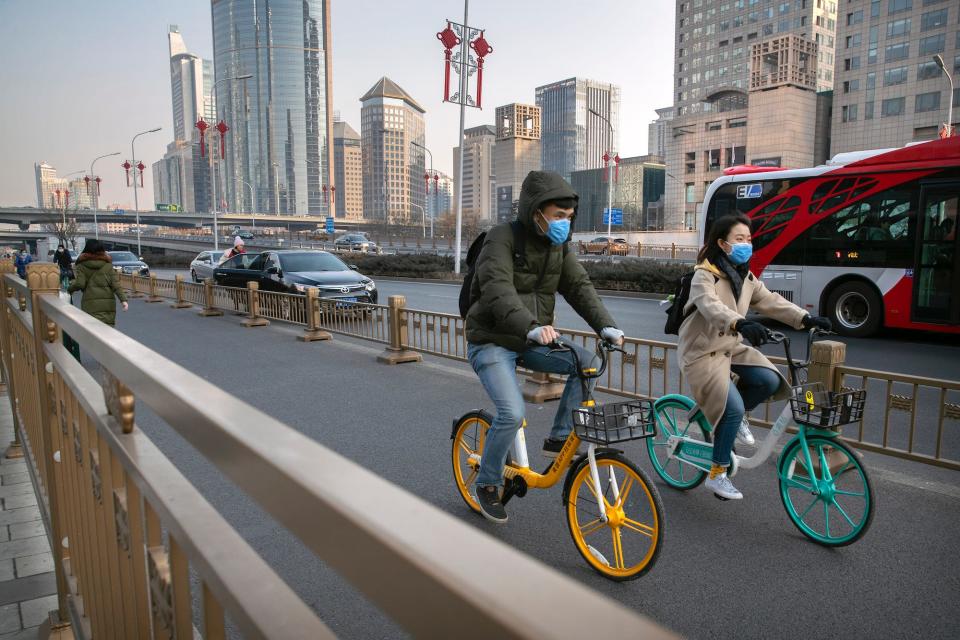 A couple wear face masks as they ride along a street in Beijing, Wednesday, Jan. 22, 2020.