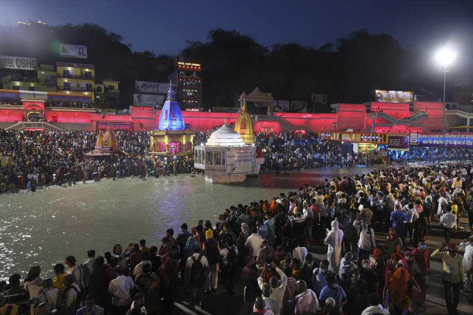 Devotees sit and pray in the evening on the ghats of the Ganges River during Kumbh Mela, or pitcher festival, one of the most sacred pilgrimages in Hinduism, in Haridwar, northern state of Uttarakhand, India, Monday, April 12, 2021. Tens of thousands of Hindu devotees gathered by the Ganges River for special prayers Monday, many of them flouting social distancing practices as the coronavirus spreads in India with record speed. (AP Photo/Karma Sonam)