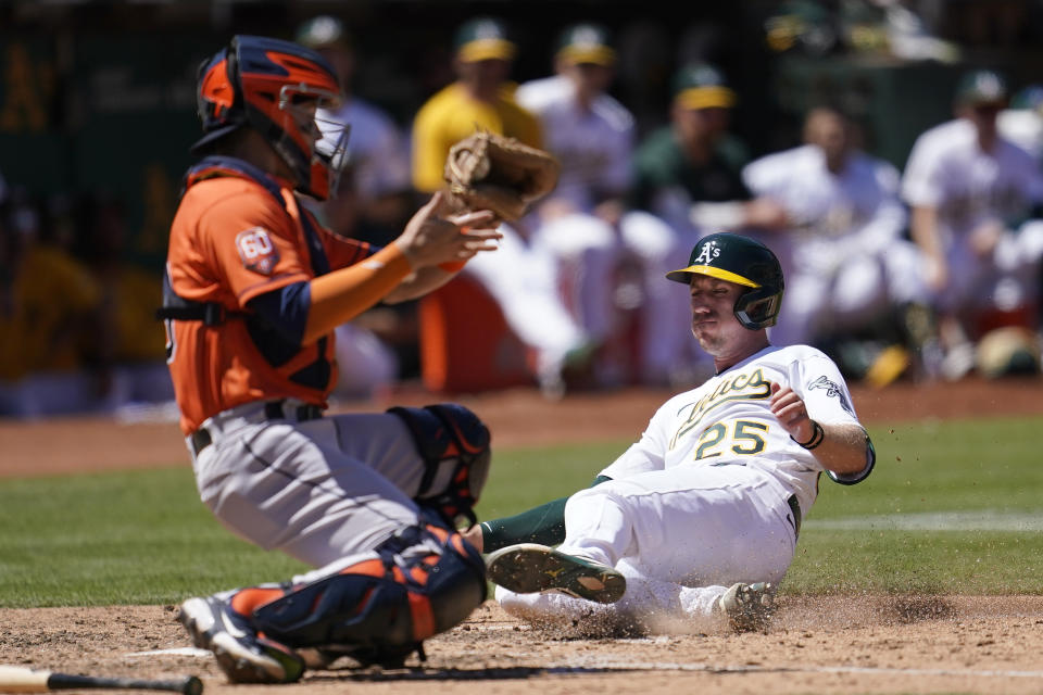 Oakland Athletics' Stephen Piscotty (25) slides home to score against Houston Astros catcher Korey Lee during the seventh inning of a baseball game in Oakland, Calif., Wednesday, July 27, 2022. (AP Photo/Jeff Chiu)
