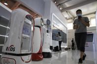 Workers prepare a display near robots at the China International Fair for Trade in Services (CIFTIS) to be held in Beijing on Friday, Sept. 4, 2020. As China recovers from the COVID-19 pandemic, business as usual is picking back up with the holding of the China International Fair for Trade in Services. Nearly 2,000 Chinese and foreign enterprises will participate and showcase their newest technology in public health and digital technology (AP Photo/Ng Han Guan)