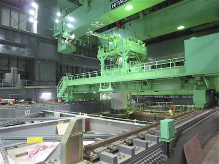 Workers wearing protective suits and masks carry out an operation to remove fuel rods from a spent fuel pool inside the No.4 reactor building at Tokyo Electric Power Co's (TEPCO) Fukushima Daiichi nuclear power plant in Fukushima prefecture November 18, 2013, in this handout photograph taken and released by TEPCO. REUTERS/Tokyo Electric Power Co/Handout via Reuters