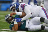 Philadelphia Eagles quarterback Jalen Hurts, bottom, is tackled by New York Giants' Reggie Ragland during the first half of an NFL football game, Sunday, Nov. 28, 2021, in East Rutherford, N.J. (AP Photo/John Munson)