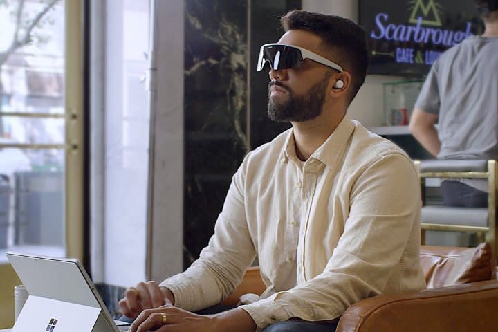 A person uses an Immersed Visor and a Surface Pro in a coffee shop.