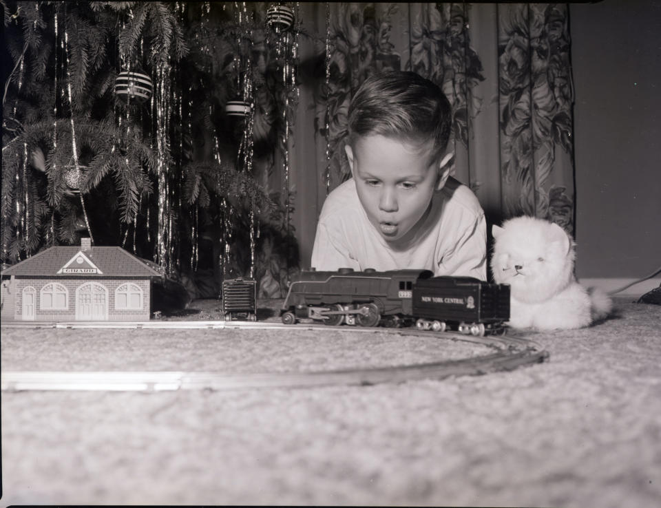 A young boy looks on in&nbsp;wonder as his model train moves around the track in this undated photograph.