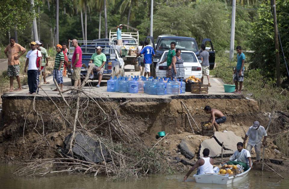 People stand on the edge of a collapsed bridge as they wait to ferry their goods via a boat across the Papagayos River, south of Acapulco, near Lomas de Chapultepec, Mexico, Wednesday, Sept. 18, 2013. Mexico was hit by the one-two punch of twin storms over the weekend, and the storm that soaked Acapulco on Sunday - Manuel -re-formed into a tropical storm Wednesday, threatening to bring more flooding to the country's northern coast. With roads blocked by landslides, rockslides, floods and collapsed bridges, Acapulco was cut off from road transport.  (Eduardo Verdugo/AP)