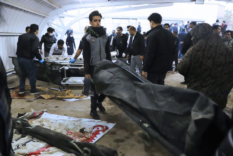 A man carries the body of a victim in a body bag following two explosions in the Iranian city of Kerman.