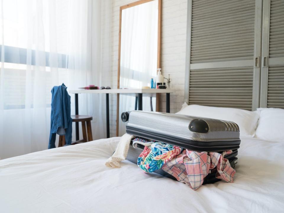 A stuffed suitcase sits on a bed.