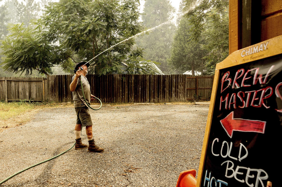 James Lowery sprays water on his friend's restaurant as the Mosquito Fire threatens Foresthill in Placer County, Calif., on Friday, Sept. 9, 2022. (AP Photo/Noah Berger)