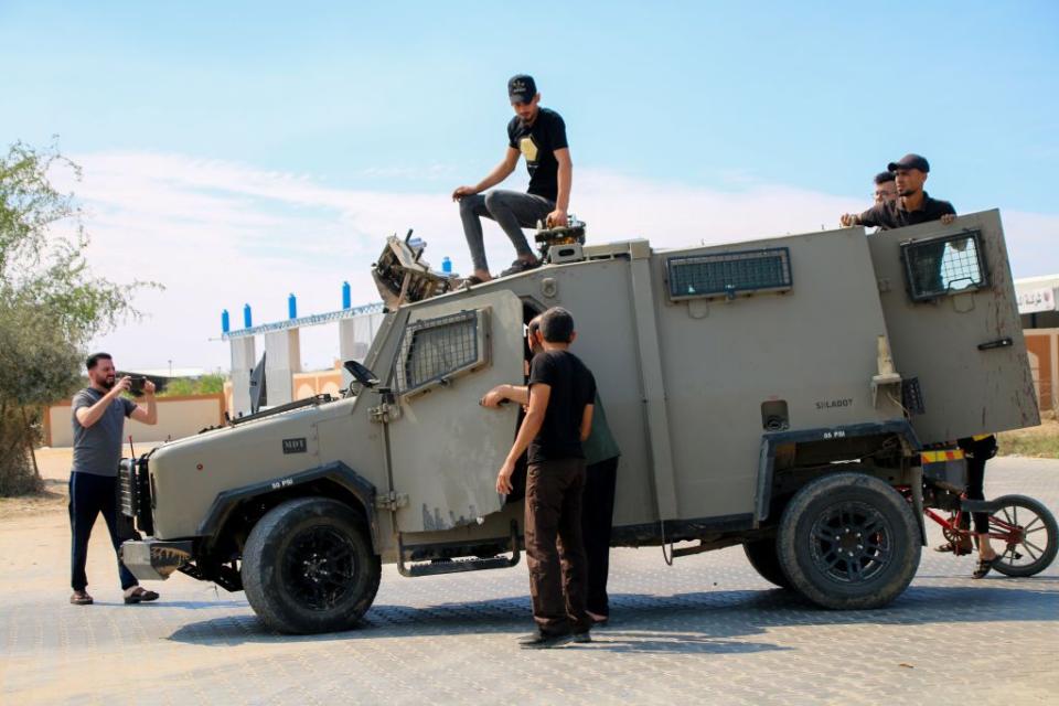 Palestinian citizens stand near an Israeli enclave seized from the Israeli occupation near the border fence between the Gaza Strip and Israel on October 7, 2023, in Gaza City, Gaza. The Palestinian militant group Hamas launched a missile attack on Israel today, with fighters simultaneously crossing the border from Gaza. Israel has declared a state of war.