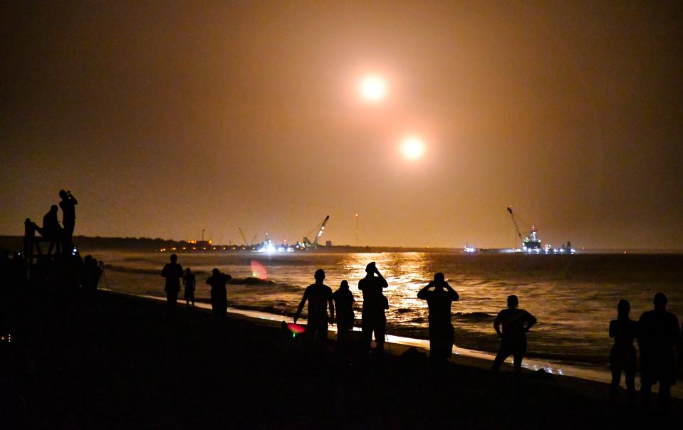 People on the beach near Cherie Down Park in Cape Canaveral watch the boosters land at Cape Canaveral Air Force Station approximately eight minutes after launch.