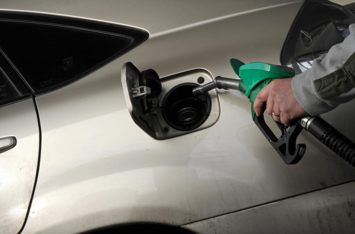 A motorist pulls the fuel pump nozzle from their car at a petrol station in Egham