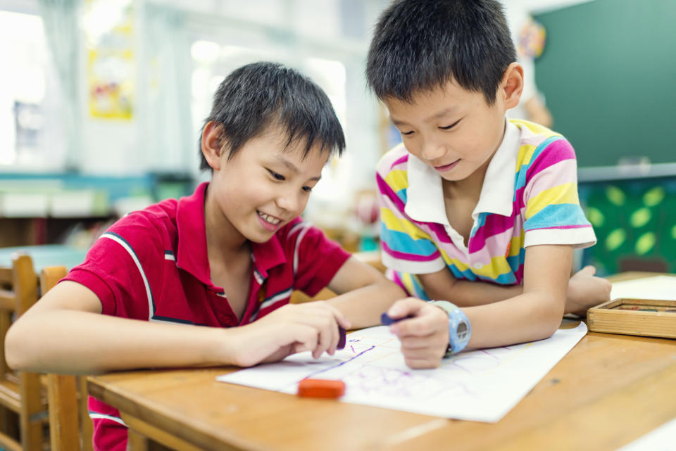 Boys are drawing by using crayons in class