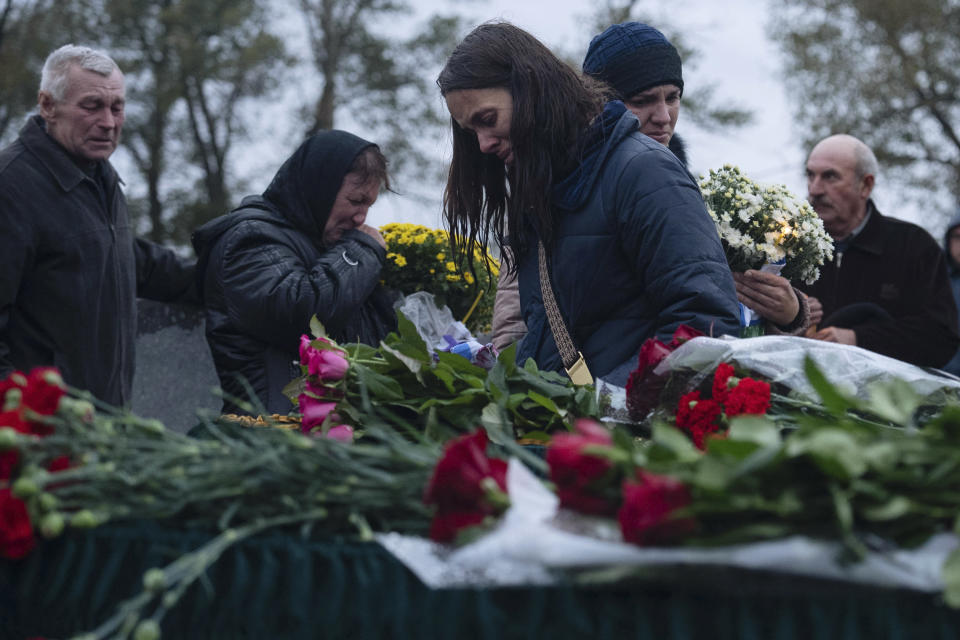 Kateryna Tarannyk, centre, reacts near coffins of her parents Tetiana Androsovych, 60, and Mykola Androsovych, 63, killed by a rocket strike, at a graveyard in the village of Hroza, near Kharkiv, Ukraine, Saturday, Oct. 7, 2023. The Ukrainian village of Hroza has been plunged into mourning by a Russian rocket strike on a village store and cafe that killed more than 50 people on Thursday, Oct. 5. (AP Photo/Alex Babenko)
