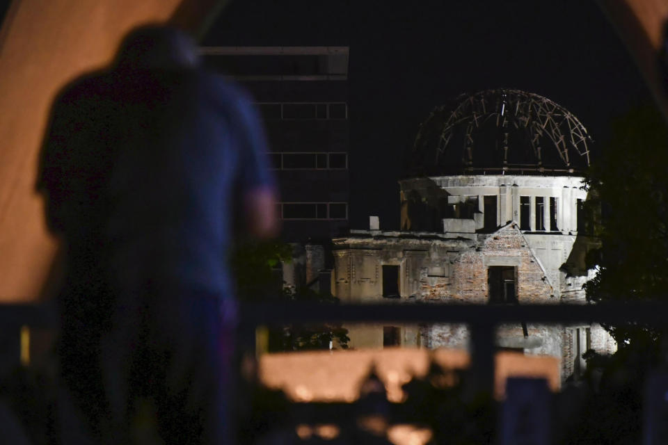 A visitor prays in front of the Atomic Bomb Dome in Hiroshima, western Japan early Friday, Aug. 6, 2021. Hiroshima on Friday marked the 76th anniversary of the world's first atomic bombing of the city. (Kyodo News via AP)