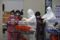 In this Friday, Feb. 21, 2020, photo, nurses in protective suits distribute meals to patients at a temporary hospital at Tazihu Gymnasium in Wuhan in central China's Hubei province. China's leadership sounded a cautious note Friday about the country's progress in halting the spread of the new virus that has now killed more than 2,200 people, after several days of upbeat messages. (Chinatopix via AP)