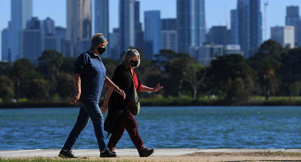 People wearing facemasks are seen exercising along Albert Park Lake in Melbourne.