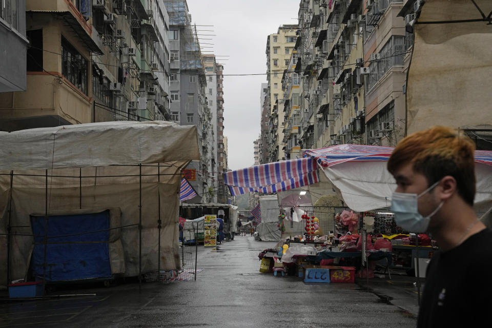 A man walks past the Ladies' Market in Mongkok district in Hong Kong, Thursday, Feb. 17, 2022. Hong Kong on Thursday reported 6,116 new coronavirus infections, as the city’s hospitals reached 90% capacity and quarantine facilities are at their limit, authorities said. (AP Photo/Kin Cheung)
