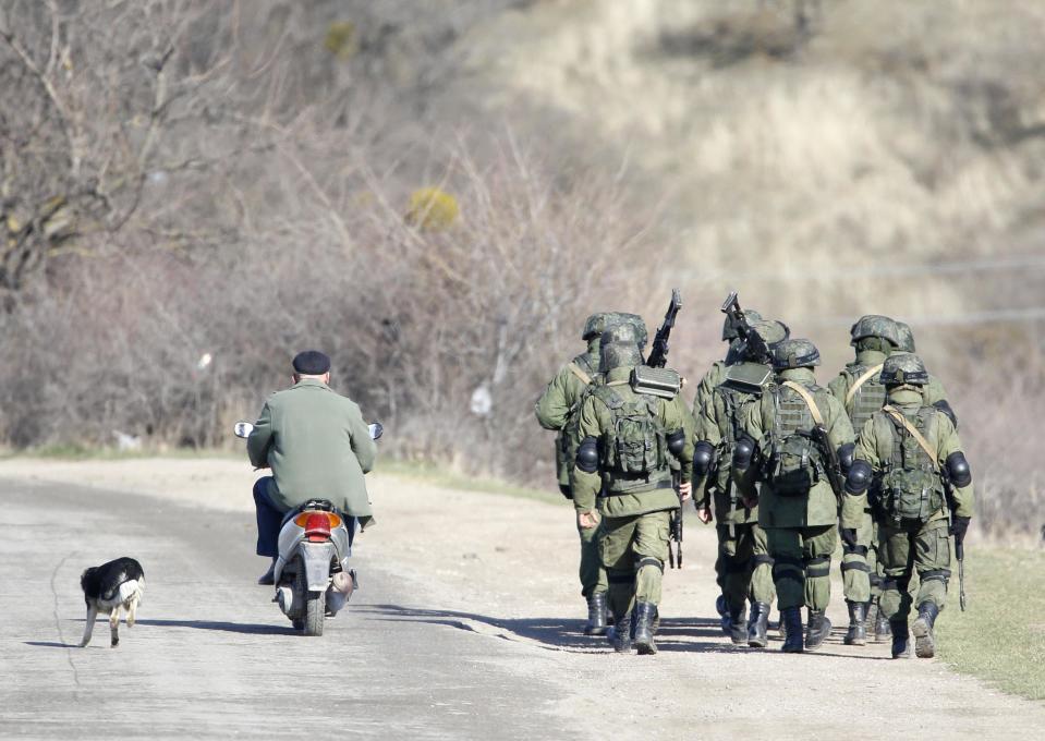 Armed men believed to be Russian servicemen march outside a Ukrainian military base in the village of Perevalnoye