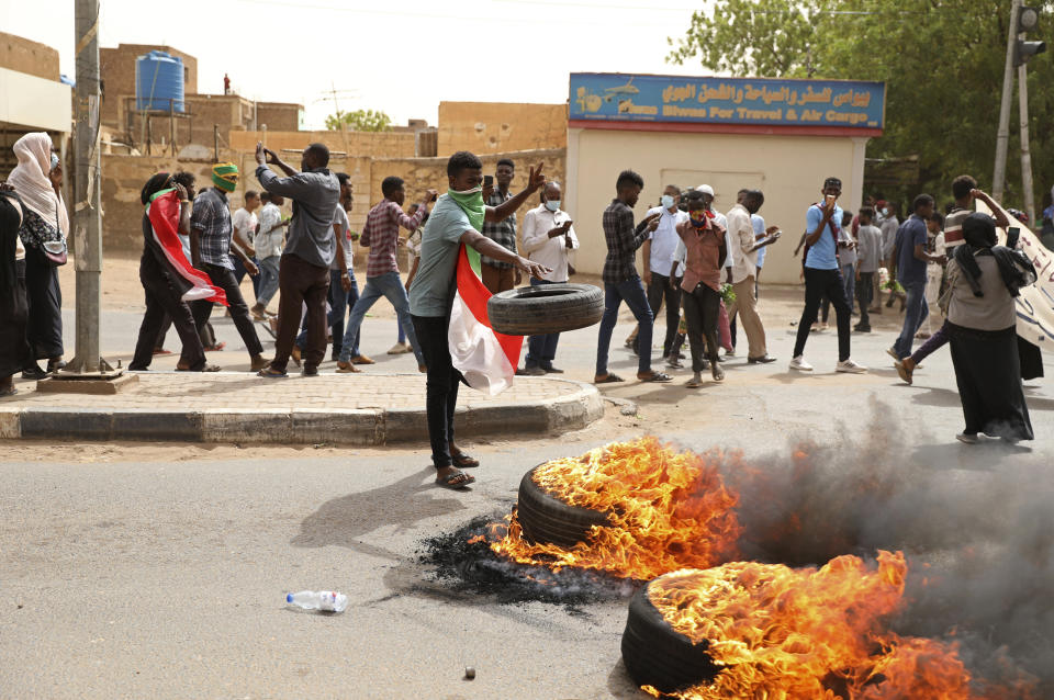 A demonstrator throws a tire on a fire during a protest over economic conditions, in Khartoum, Sudan, Wednesday, June 30, 2021. The World Bank and the International Monetary Fund said in a joint statement Tuesday, that Sudan has met the initial criteria for over $50 billion in foreign debt relief, another step for the East African nation to rejoin the international community after nearly three decades of isolation. (AP Photo/Marwan Ali)