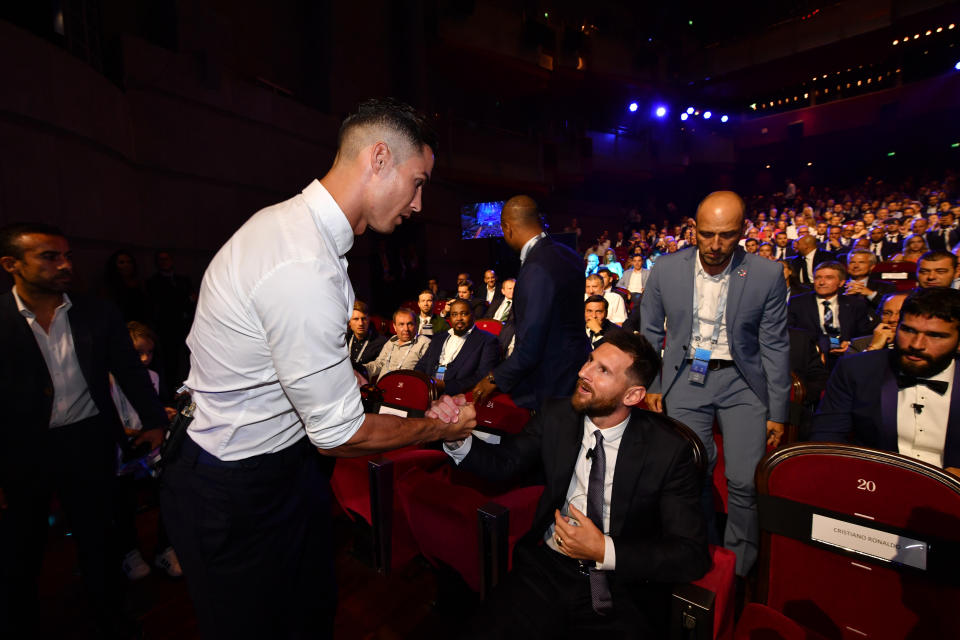 Messi, sentado, y Cristiano Ronaldo, de pie, se saludan en los asientos de un auditorio antes de empezar el sorteo de la Champions.