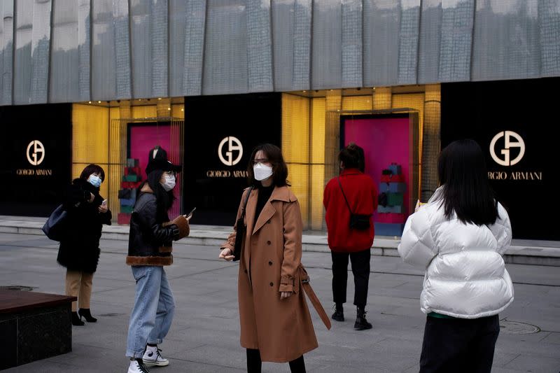 People wearing face masks are seen outside a Giorgio Armani store at a shopping mall in Wuhan