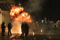 A petrol bomb thrown by protesters explodes near riot police in front of the parliament during clashes in Athens.