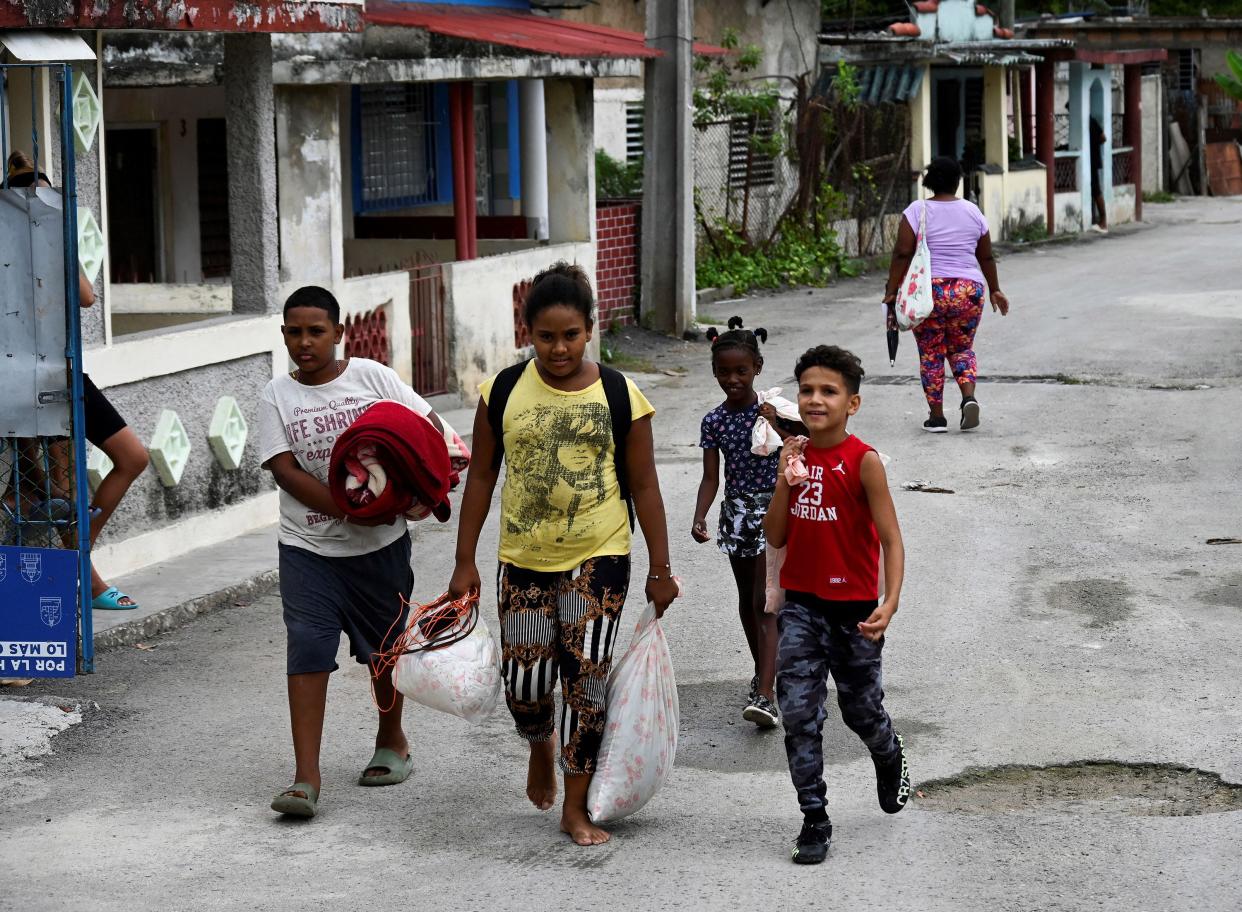 Cuban children carry personal belongings to a safe place in the Fanguito neighborhood in Havana, on Sept. 26, 2022, ahead of the arrival of Hurricane Ian. Cuba declared an emergency alert in its six most western provinces as fast-approaching Hurricane Ian was moving northwest towards Cuba and the Cayman Islands with maximum sustained winds of 85 miles per hour.