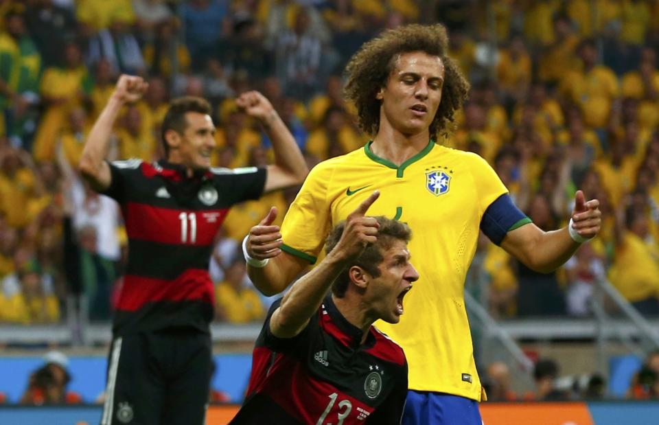 Germany's Thomas Mueller celebrates after scoring a goal, as Brazil's David Luiz watches, during their 2014 World Cup semi-finals at the Mineirao stadium in Belo Horizonte July 8, 2014. REUTERS/Eddie Keogh