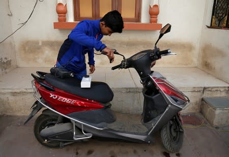 FILE PHOTO: A boy prepares to recharge his electric scooter outside his home in Ahmedabad