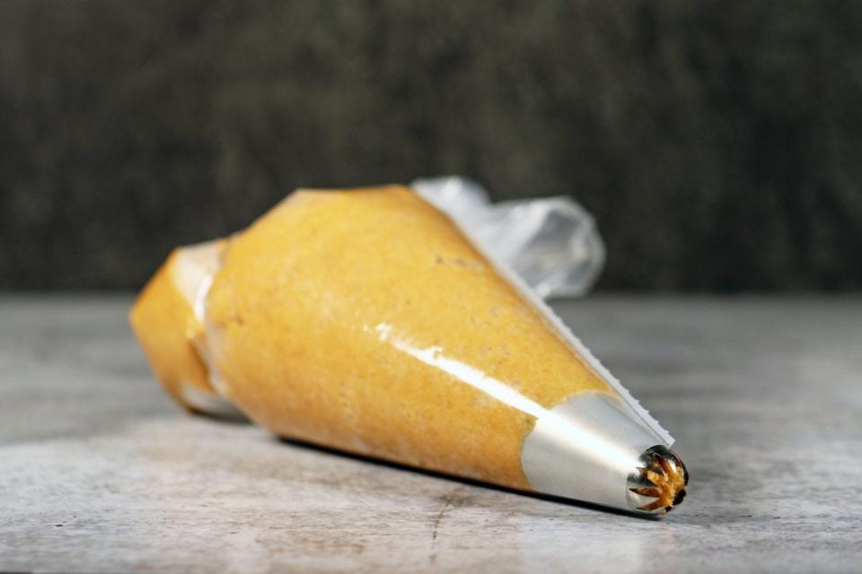 Churro dough in a piping tube with star nozzle attachment.