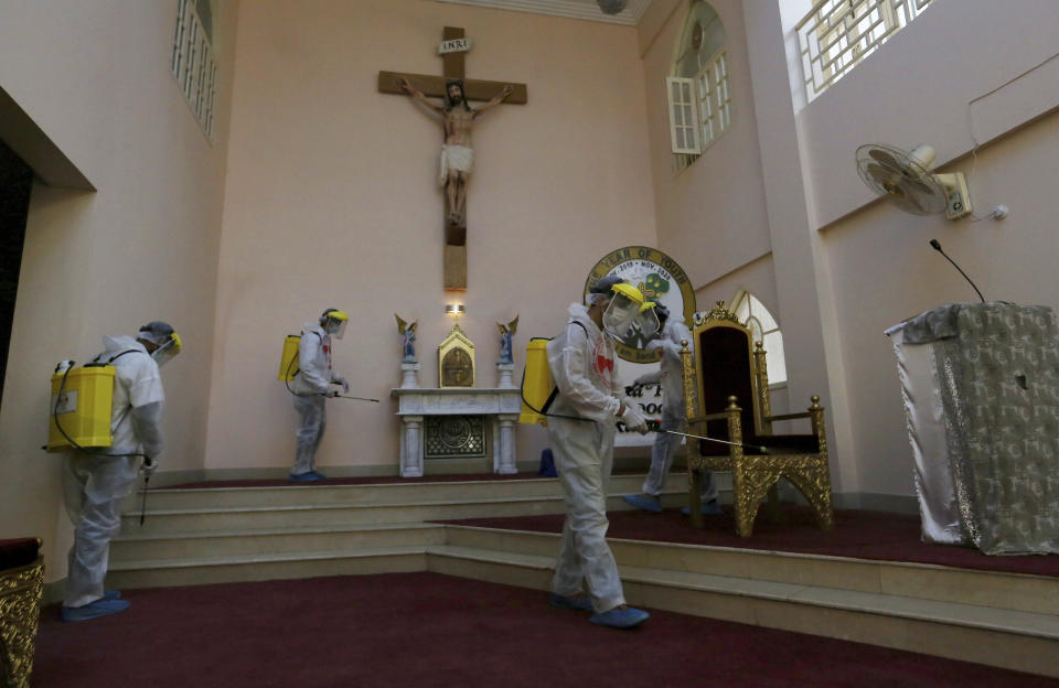 Volunteers spray disinfectant in the main hall of St Paul's Parish in an effort to curb the spread of the coronavirus, ahead of Christmas celebrations, in Karachi, Pakistan, Tuesday, Dec. 22, 2020. (AP Photo/Fareed Khan)