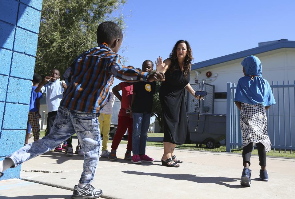 Director Lynette Faulkner, middle, tries to slow down a student at Valencia Newcomer School between classes Thursday, Oct. 17, 2019, in Phoenix. Children from around the world are learning the English skills and American classroom customs they need to succeed at so-called newcomer schools. Valencia Newcomer School in Phoenix is among a handful of such public schools in the United States dedicated exclusively to helping some of the thousands of children who arrive in the country annually. (AP Photo/Ross D. Franklin)