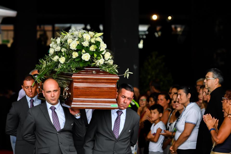 Pallbearers carry a coffin during a funeral service for some of the victims of a collapsed highway bridge, in Genoa's exhibition center Fiera di Genova, Italy, Saturday, Aug. 18, 2018. Saturday has been declared a national day of mourning in Italy and includes a state funeral at the industrial port city's fair grounds for those who plunged to their deaths as the 45-meter (150-foot) tall Morandi Bridge gave way Tuesday (Simone Arveda/ANSA via AP)