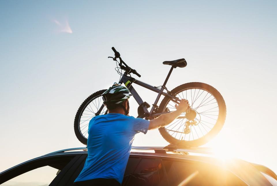 man mounting bike to vehicle roof