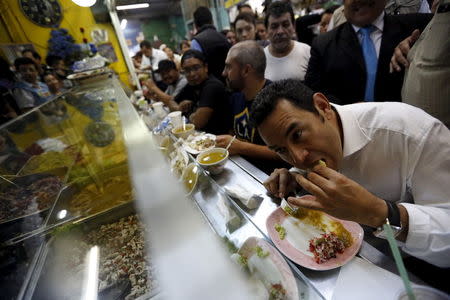 Guatemalan presidential candidate Jimmy Morales (R) eats lunch at the central market in Guatemala City, October 21, 2015. REUTERS/Jorge Dan Lopez