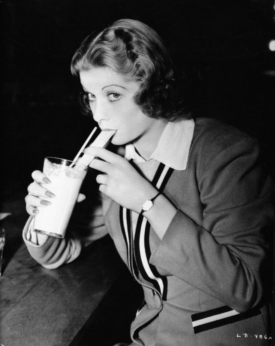 1938: Sipping a shake through a straw wearing classic '30s clothes.