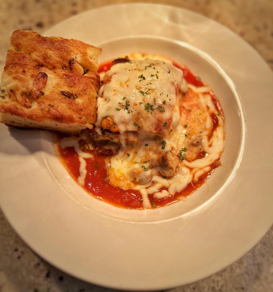 Lasagna served with focaccia bread and half Caesar salad at Noosh Nosh restaurant in Louisville.