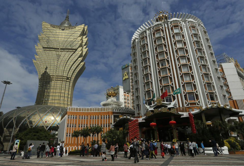 In this Feb. 1, 2014 photo, tourists gather in front of old and new Casino Lisboa during a Chinese New Year celebration in Macau. The annual holiday is the busiest time of year for the former Portuguese colony, which became a special Chinese region in 1999. Many of the millions of mainland Chinese on the move during the holiday, often referred to as the world’s biggest migration, head to Macau during the festival. (AP Photo/Vincent Yu)