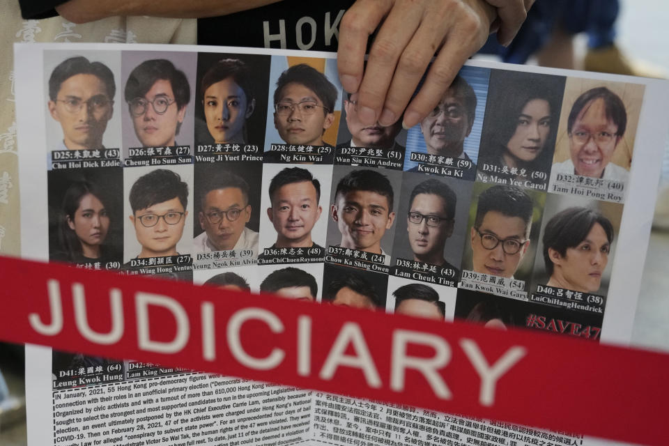 A supporter holds a placard with the photos of some of the 47 pro-democracy defendants outside a court in Hong Kong, Thursday, July 8, 2021. A court hearing for 47 pro-democracy activists charged with conspiracy to commit subversion under the security law over their involvement in an unofficial primary election last year that authorities said was a plot to paralyze Hong Kong's government. (AP Photo/Kin Cheung)