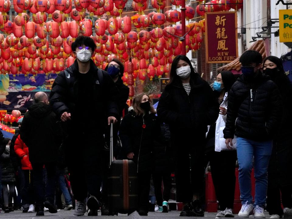 Members of the public wearing face masks stroll through Chinatown in London (AP)